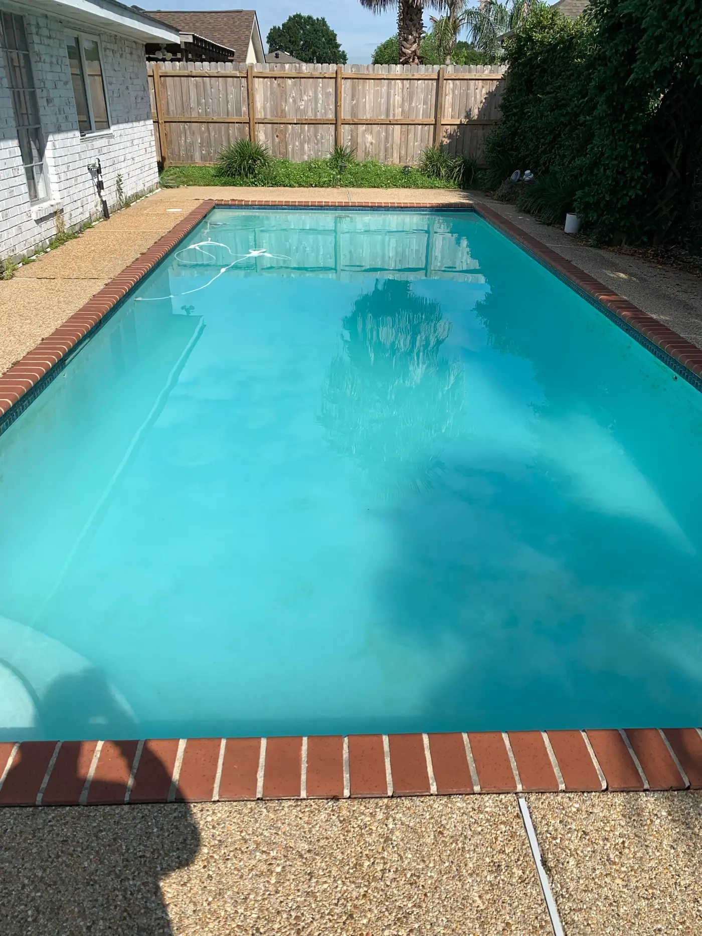 A clear blue rectangular pool with brick coping after Baehr's cleaning