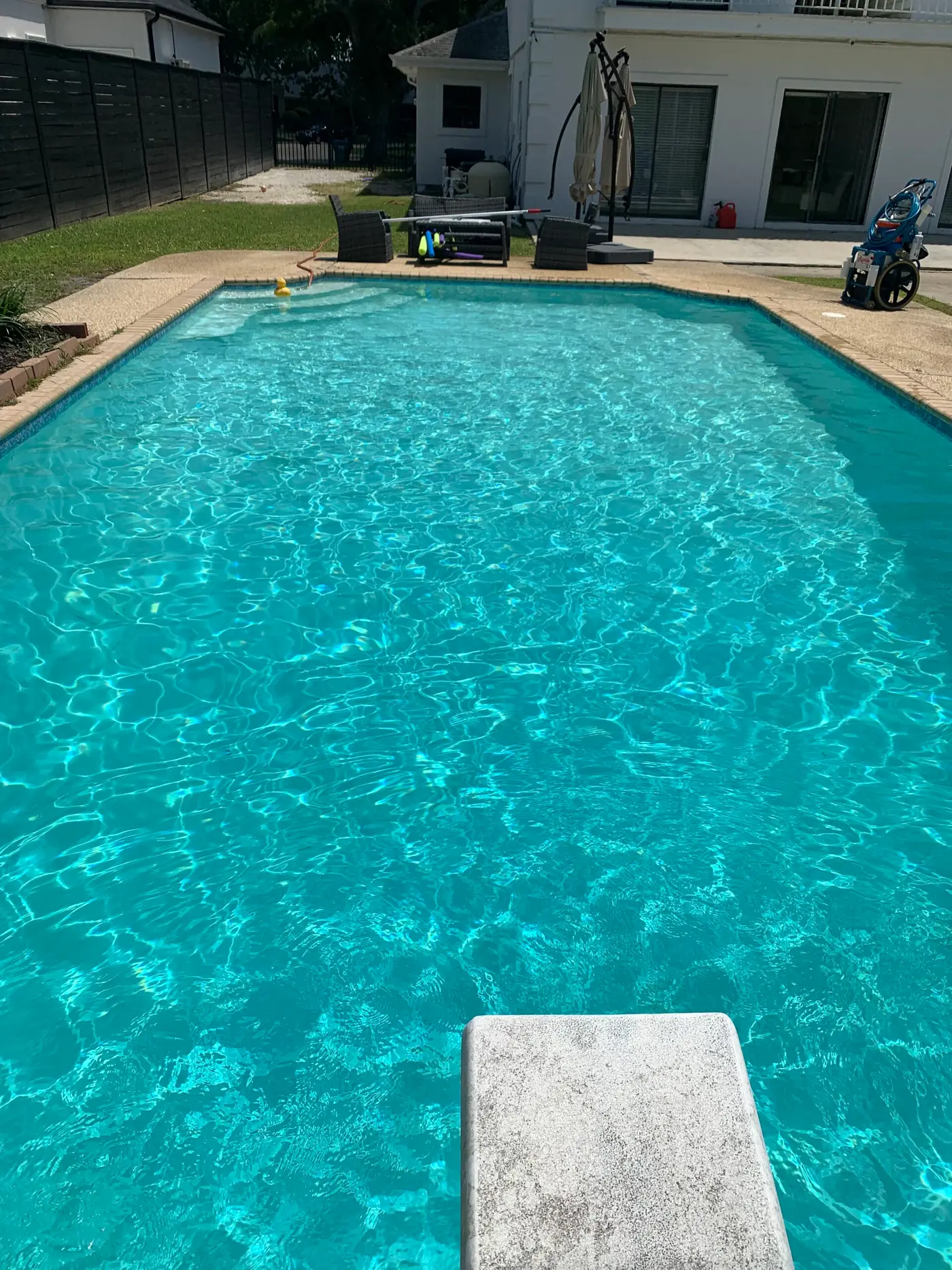 Sparkling, well-circulated pool seen from the diving board, a cleaning cart on the deck
