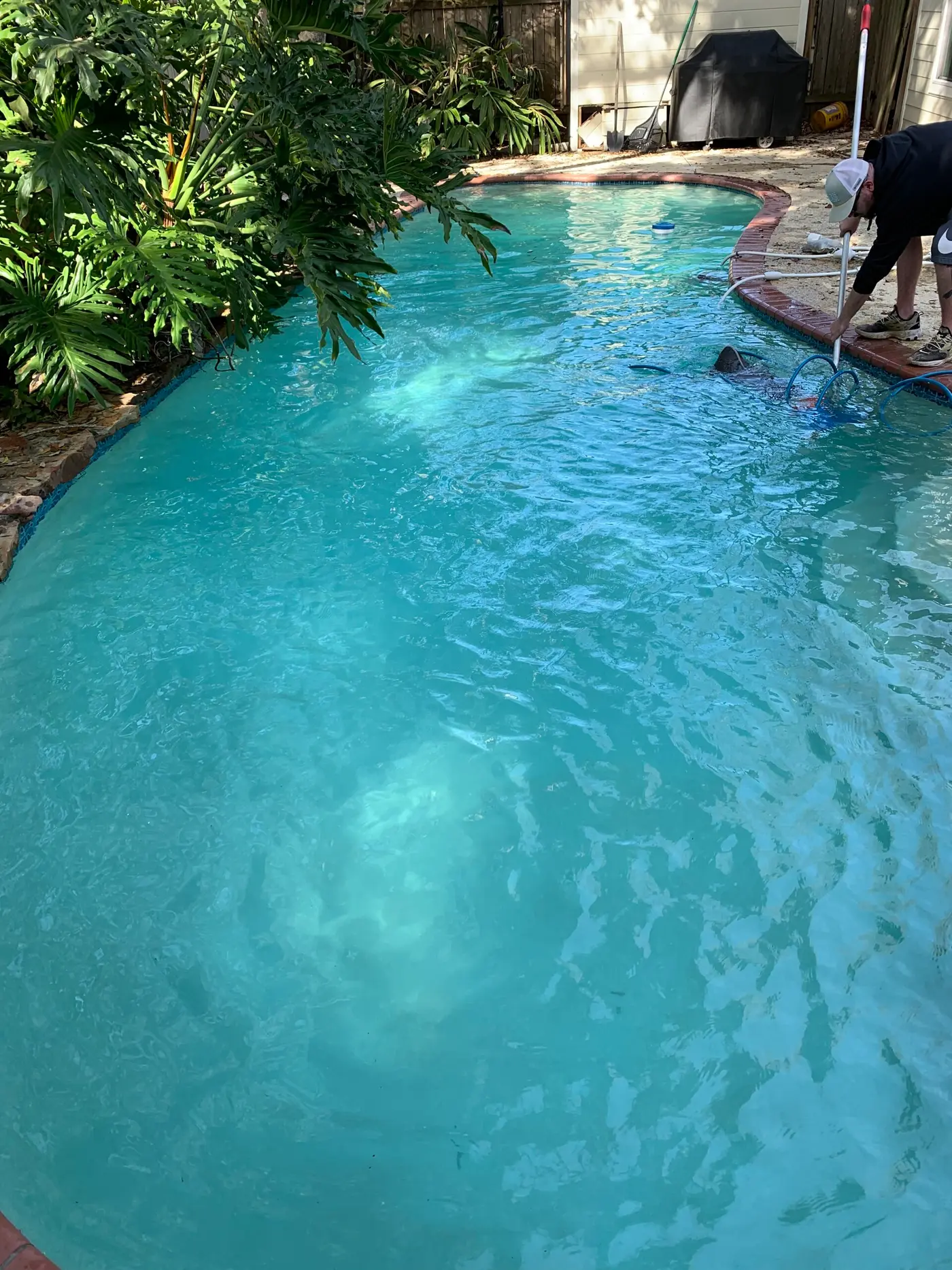 A Baehr's technician vacuuming a kidney-shaped pool